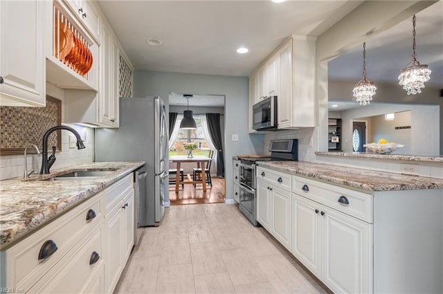 kitchen with a notable chandelier, backsplash, appliances with stainless steel finishes, and a sink