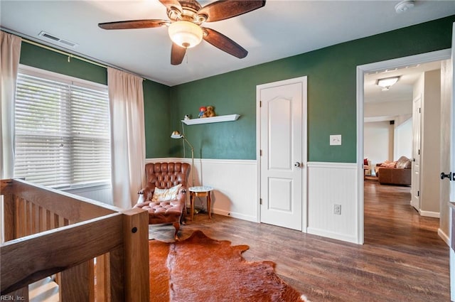 bedroom with visible vents, a wainscoted wall, wood finished floors, and ceiling fan