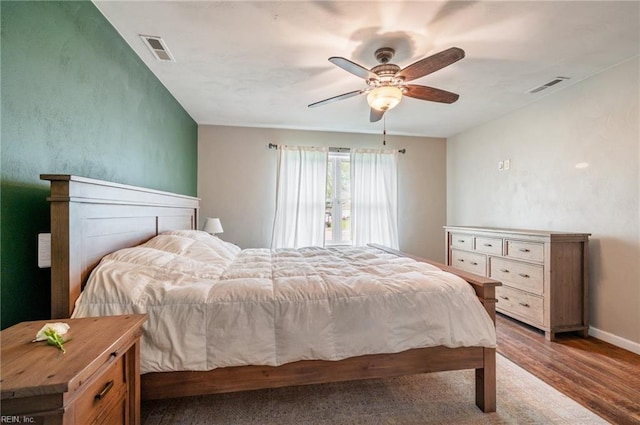 bedroom featuring baseboards, wood finished floors, visible vents, and a ceiling fan