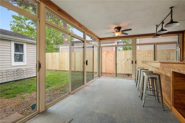 unfurnished sunroom with outdoor dry bar, a healthy amount of sunlight, and a ceiling fan