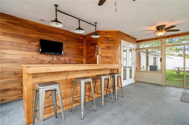 bar featuring carpet, wooden walls, visible vents, a ceiling fan, and french doors