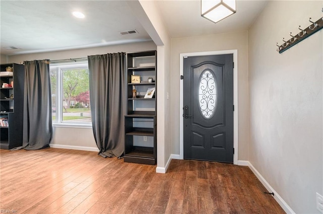 foyer featuring visible vents, baseboards, and wood finished floors