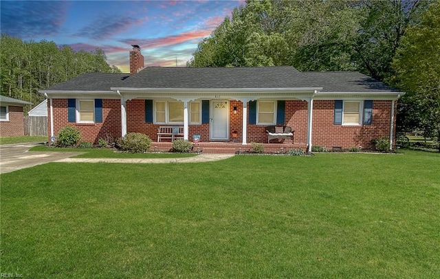 single story home with a chimney, a lawn, and covered porch