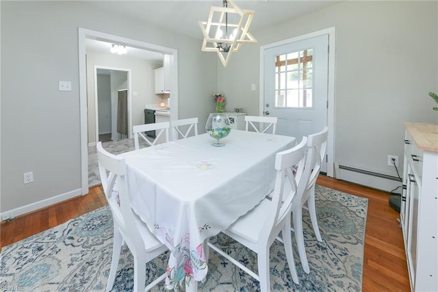 dining room with a baseboard heating unit, wood finished floors, baseboards, and a notable chandelier