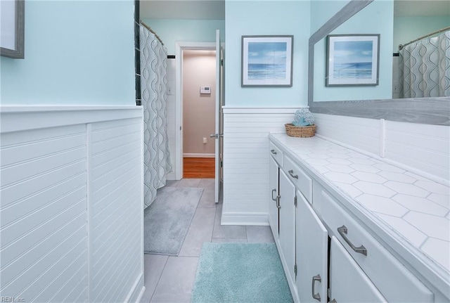 full bathroom featuring a wainscoted wall, vanity, and tile patterned flooring