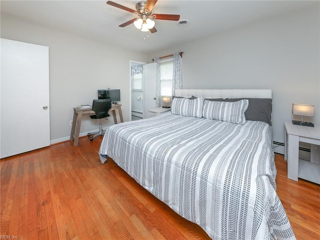 bedroom featuring baseboards, a ceiling fan, wood finished floors, and visible vents