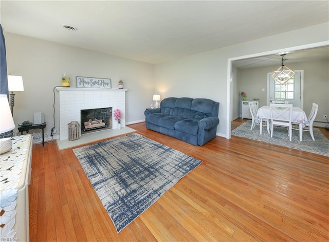 living room featuring visible vents, baseboards, wood finished floors, and a fireplace