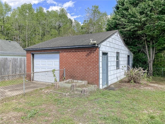 garage featuring fence and a garden