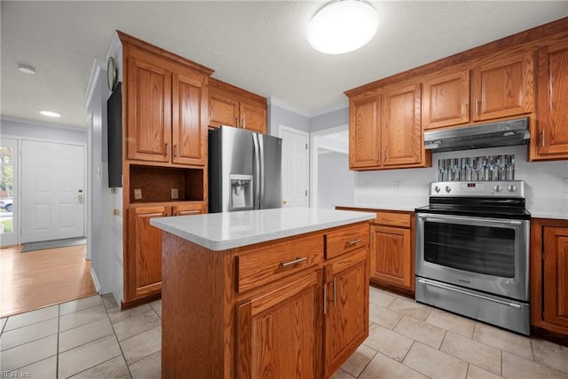 kitchen featuring crown molding, brown cabinetry, light tile patterned floors, appliances with stainless steel finishes, and under cabinet range hood