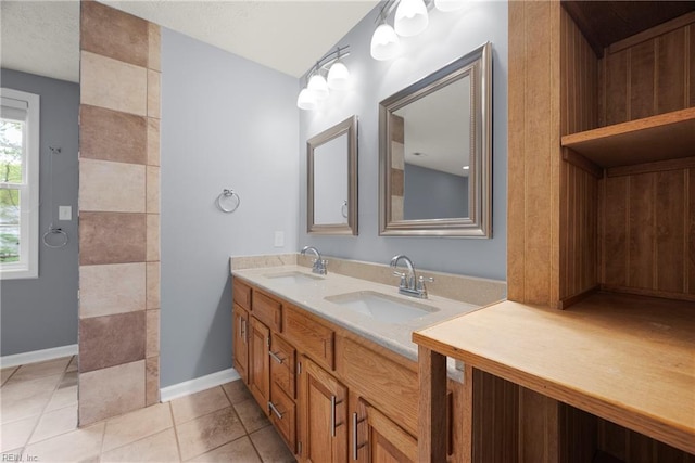 full bath with tile patterned floors, baseboards, a sink, and double vanity