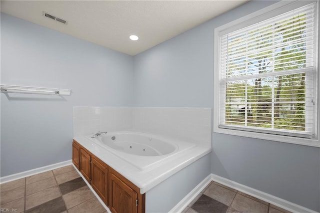 full bath with baseboards, visible vents, a jetted tub, and a healthy amount of sunlight