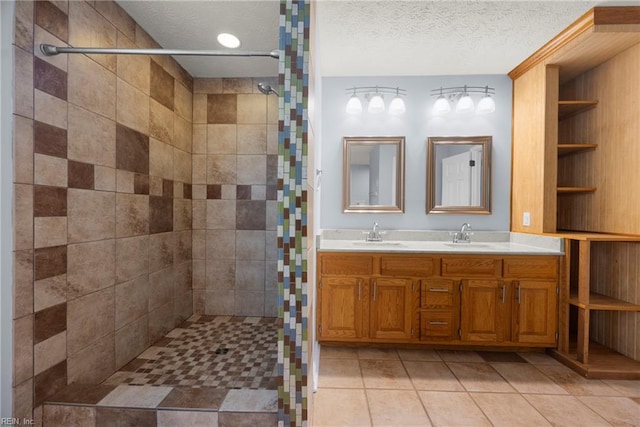 bathroom with tile patterned floors, a sink, a textured ceiling, and tiled shower