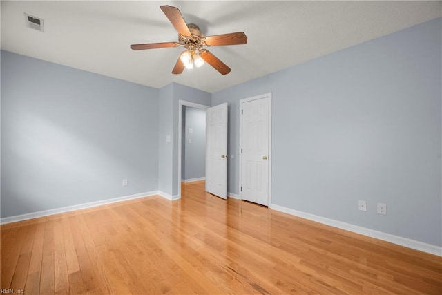 empty room with light wood-type flooring, baseboards, ceiling fan, and visible vents