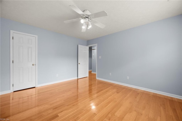 unfurnished bedroom with ceiling fan, baseboards, a textured ceiling, and light wood finished floors