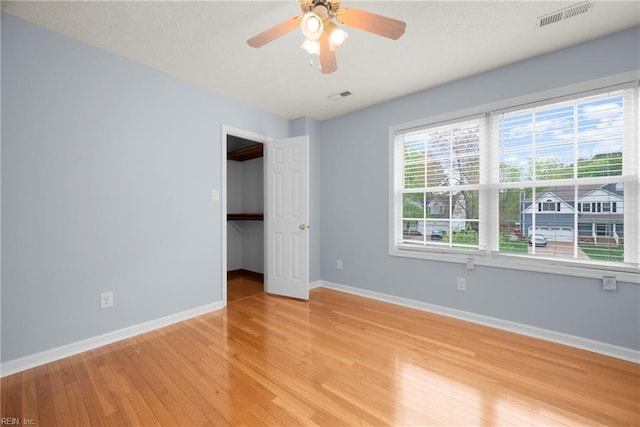 spare room featuring baseboards, a ceiling fan, light wood finished floors, and visible vents
