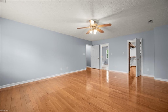 unfurnished room with light wood finished floors, visible vents, baseboards, a textured ceiling, and ceiling fan