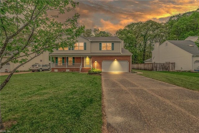 view of front of house with driveway, covered porch, fence, a garage, and brick siding