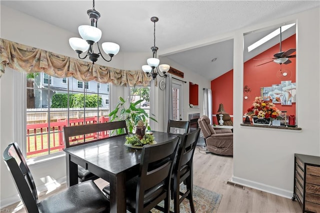 dining room featuring vaulted ceiling, light wood-type flooring, and plenty of natural light