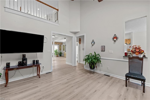 entrance foyer featuring a towering ceiling, wood finished floors, and baseboards