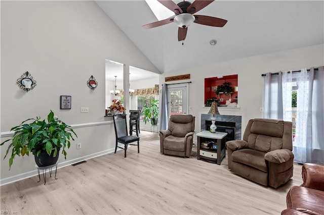 living area with high vaulted ceiling, a ceiling fan, light wood-style flooring, a fireplace, and visible vents