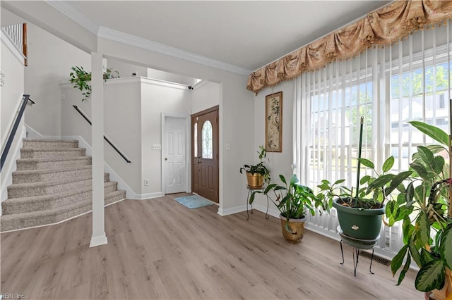 foyer featuring light wood-type flooring, baseboards, stairs, and ornamental molding