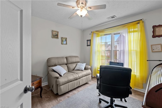 office with wood finished floors, a textured ceiling, ceiling fan, baseboards, and visible vents
