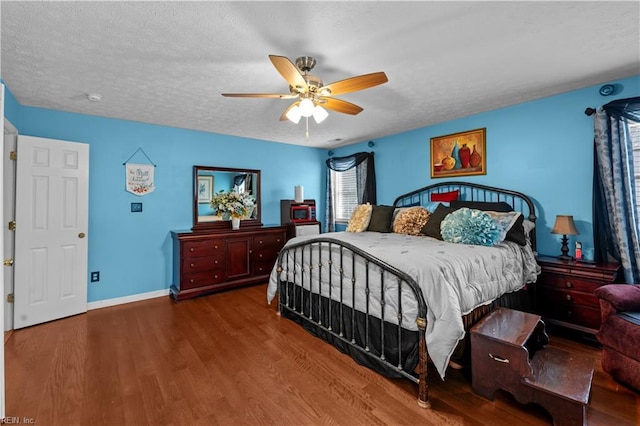 bedroom with baseboards, wood finished floors, a textured ceiling, and ceiling fan