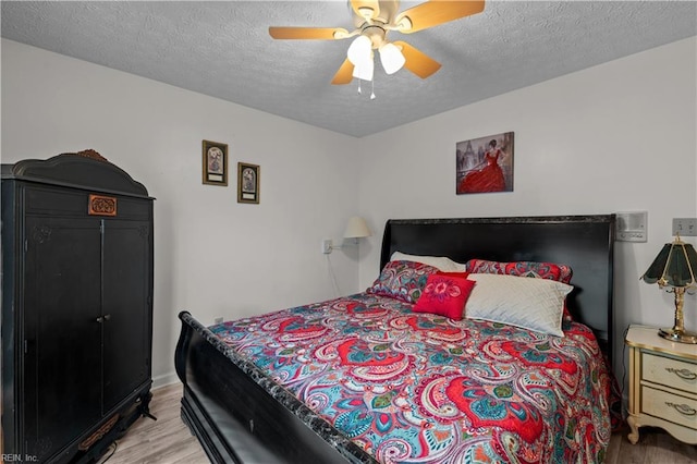 bedroom with light wood-type flooring, baseboards, a textured ceiling, and ceiling fan