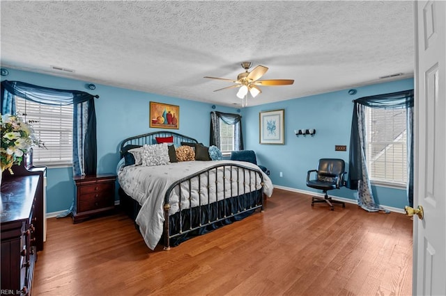 bedroom featuring baseboards, multiple windows, and wood finished floors
