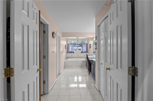 hall with baseboards, a notable chandelier, and light tile patterned floors
