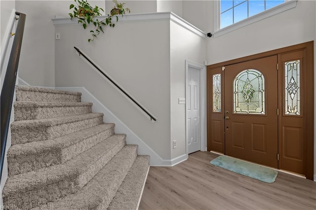 foyer entrance featuring baseboards, wood finished floors, a wealth of natural light, and stairway