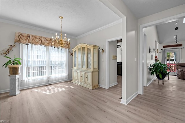 unfurnished dining area featuring crown molding, a textured ceiling, light wood-type flooring, baseboards, and a notable chandelier