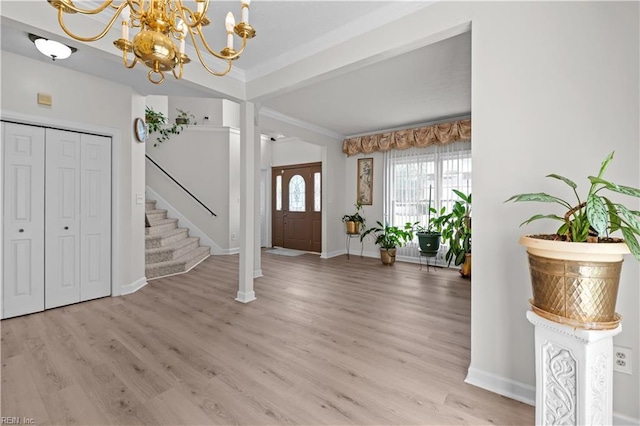 foyer with stairway, crown molding, a chandelier, light wood-style flooring, and baseboards