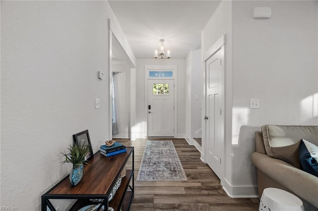 entryway with an inviting chandelier, wood finished floors, and baseboards