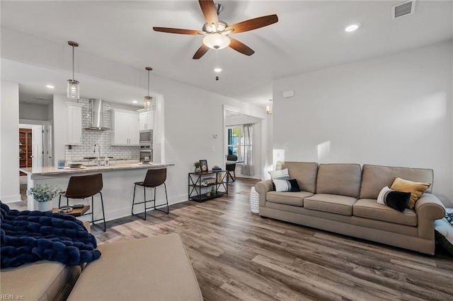 living room with baseboards, visible vents, recessed lighting, wood finished floors, and ceiling fan