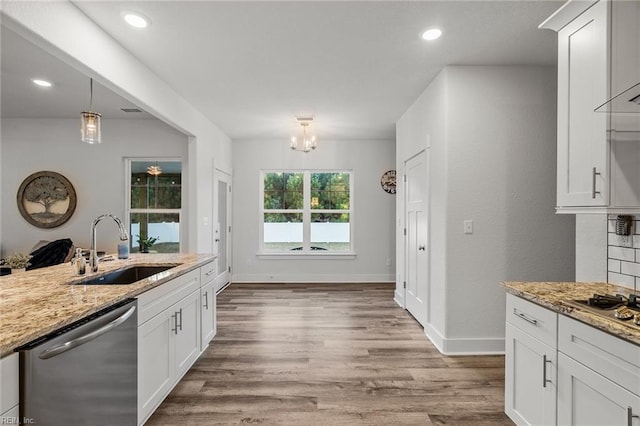 kitchen with light wood finished floors, stainless steel appliances, white cabinets, and a sink