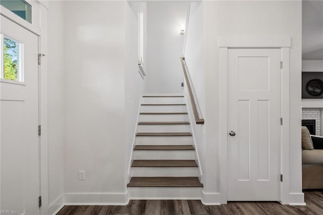 stairs featuring baseboards, wood finished floors, and a fireplace