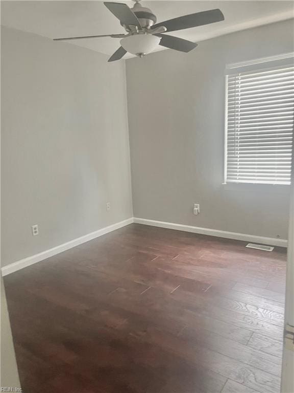 spare room with dark wood finished floors, baseboards, a ceiling fan, and visible vents