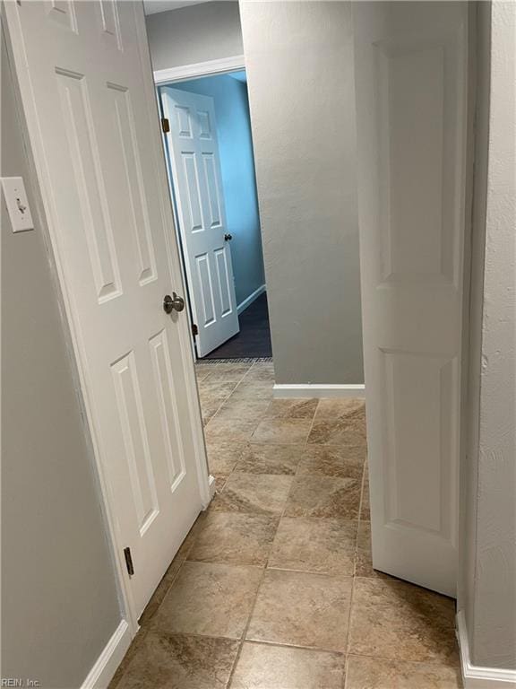corridor with baseboards and stone finish flooring