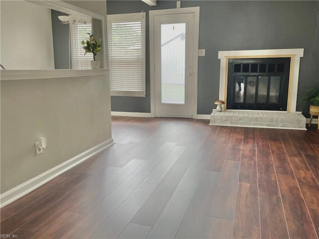 unfurnished living room featuring baseboards, a glass covered fireplace, and wood finished floors