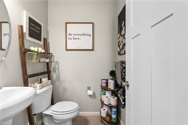 half bathroom with tile patterned flooring, toilet, baseboards, and a sink