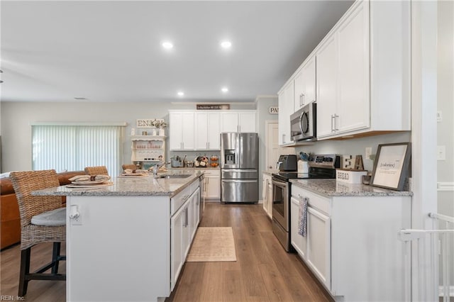 kitchen with white cabinets, stainless steel appliances, a breakfast bar, and a sink