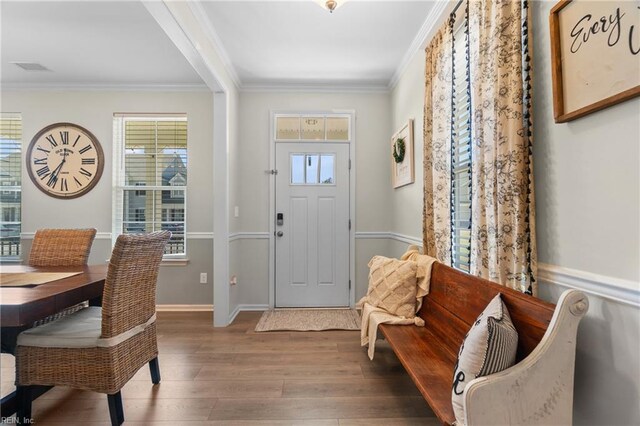 foyer entrance with wood finished floors, a healthy amount of sunlight, baseboards, and ornamental molding