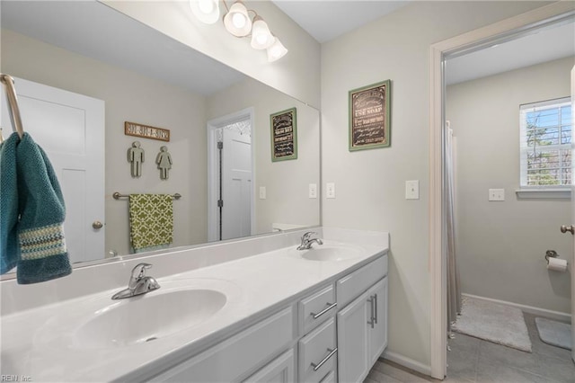bathroom with tile patterned flooring, baseboards, a sink, and double vanity