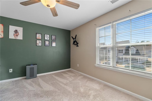 carpeted spare room featuring baseboards, a ceiling fan, and visible vents
