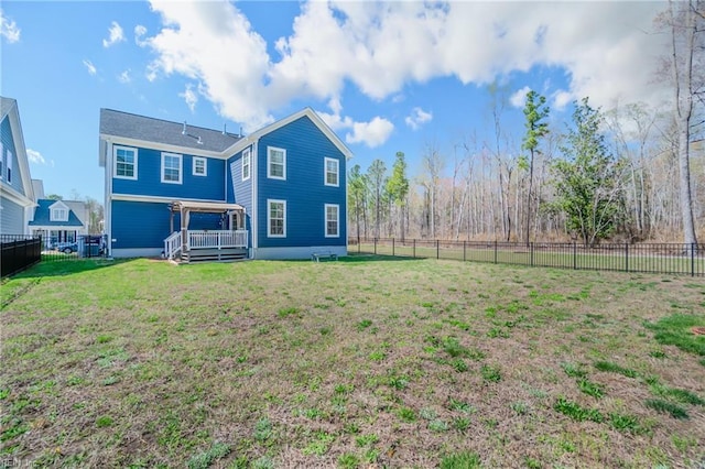 rear view of property featuring a lawn, a wooden deck, and a fenced backyard