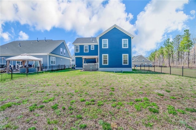 rear view of property featuring a fenced backyard, a gazebo, and a yard
