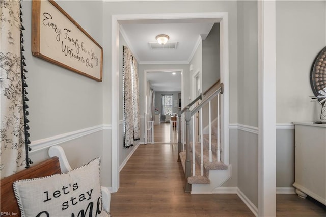 hall featuring stairs, wood finished floors, baseboards, ornamental molding, and visible vents
