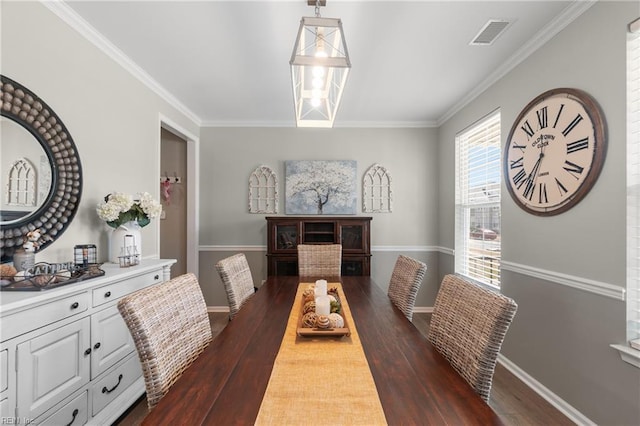 dining space featuring wood finished floors, visible vents, crown molding, and baseboards