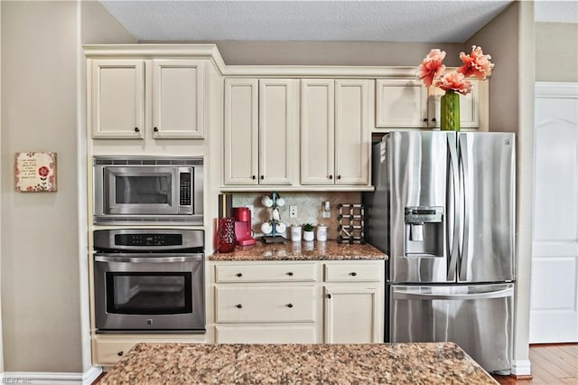 kitchen with decorative backsplash, stone counters, wood finished floors, and appliances with stainless steel finishes